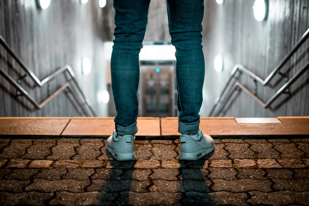 Persoon staat boven aan de trap, als een symbolische start van ontspannen met taak beginnen na hypnose tegen uitstelgedrag